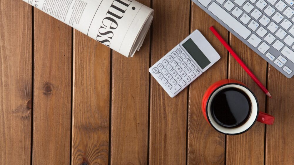image of a newspaper, calculator, cup of coffee and a keyboard